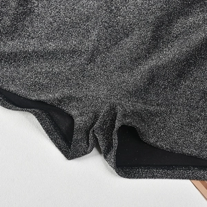 Detailed macro view of sparkling silver sequins on a high-stretch black bodysuit fabric