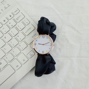 Detail of creative women's watch with black ribbon strap and colorful dotted dial markers