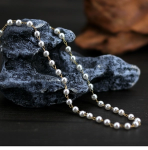 Detailed close-up of elegant white pearls with golden metal links on a textured stone base