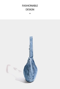 Detail of blue washed denim hobo bag with silver metal eyelets on the wide shoulder strap