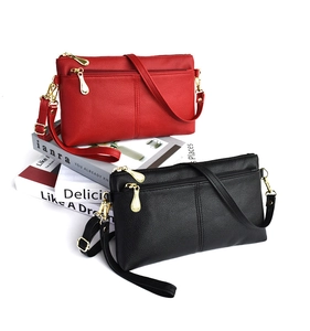 Detail of red and black lychee grain leather crossbody bags with double zippers