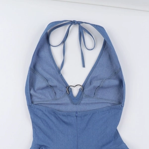 Dettaglio dello scollo a V in denim con fibbia in metallo a forma di cuore e trama tessuto