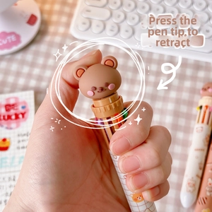 Close-up of a multi-color push-button pen featuring cute 3D bear decoration and grid pattern
