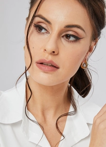 Close-up of minimalist gold egg-shaped earrings on a model with metallic finish