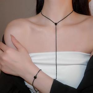 Close-up of elegant black circular pendant necklace and matching tassel bracelet set