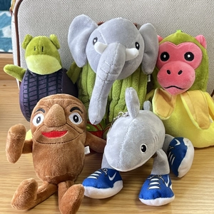 Variety of plush animal keychains including elephant and shark on wooden surface
