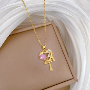 Close-up of golden heart necklace with pink zircon on a beige leather jewelry box