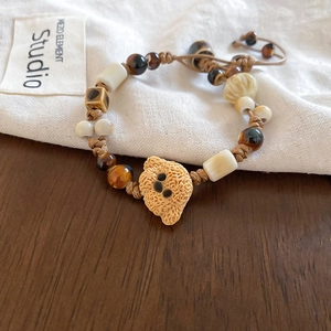 Close-up of handmade woven bracelet with ceramic beads and a cute yellow teddy bear charm