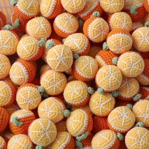 Close-up of handmade crochet orange charms crafted with vibrant orange and yellow yarn