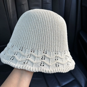Close-up of cream knit bucket hat featuring vertical ribs and wavy hollow patterns
