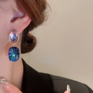 Vintage geometric oval earrings with blue and purple crystals and gold plating on female model