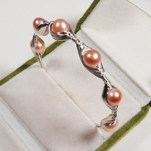 Detail of handmade wire-wrapped bracelet with pink freshwater pearls in a velvet jewelry box