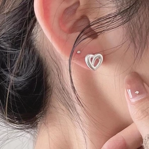 Stereo heart-shaped 925 sterling silver hoop earrings worn by a model in a close-up view