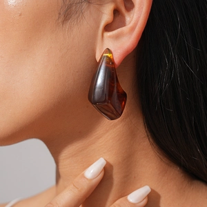 Close-up of geometric amber resin earrings with irregular facets on female model