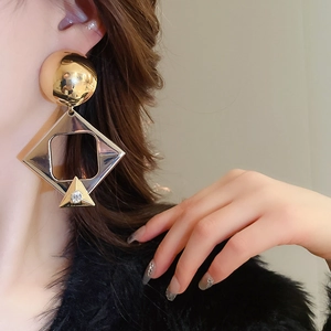 Detailed view of oversized geometric earrings with metallic diamonds on female model