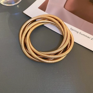 Close-up of golden multi-layer elastic snake chain bracelet with textured metal surface