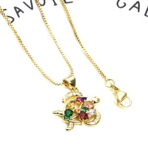 Macro shot of gold turtle pendant featuring colorful zircons and a fine box chain necklace