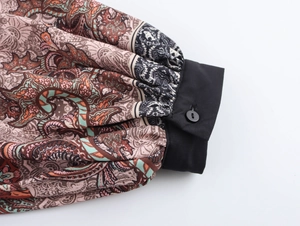 Close-up of ethnic paisley print sleeve with black buttoned cuff detail on blouse
