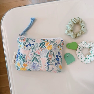 Detailed close-up of a floral cotton mini pouch with zipper and simple wish label