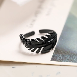 Macro shot of a black lacquer feather-shaped open ring placed on a vintage book page