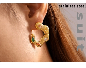 Detail of twisted gold C-shape stainless steel earring set with colorful zircons on model