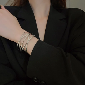 Detail of minimalist multilayer silver bangle with overlapping geometric metal lines on wrist