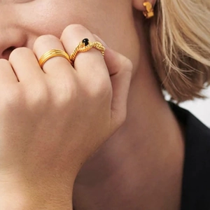 Detailed view of 18K gold stackable rings with black gemstone and matching hoop earring