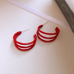 Close-up of red multi-layer C-shaped earrings with a glossy finish and silver needle