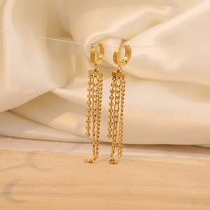 Detailed view of golden long tassel earrings with mixed chain styles on white silk