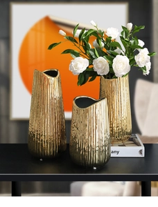 Three-piece set of gold ceramic vases with vertical texture on a modern black table