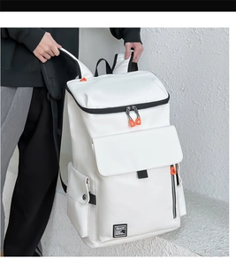 Detail of white large capacity travel backpack with orange zipper pulls and black straps