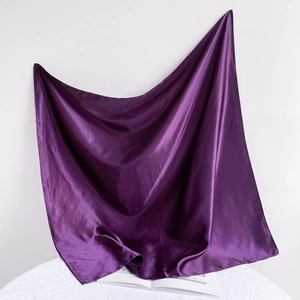 Detail view of purple satin square scarf with smooth glossy finish on white background