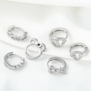 Elegant silver geometric hoop earrings set with zirconia on white silk background