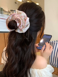 Detailed view of a white floral scrunchie with pink edges worn in a stylish ponytail