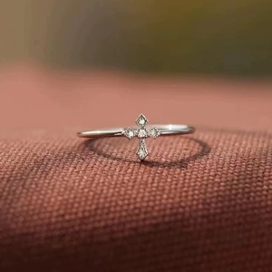 Macro shot of a slim silver cross ring with sparkling zircon stones and beaded edges