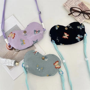 Vue détaillée de trois étuis à lunettes en toile avec broderies de papillons multicolores