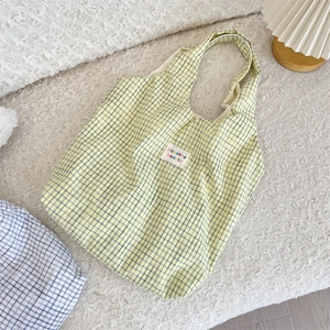 Gros plan du sac fourre-tout à carreaux jaunes avec étiquette sur tapis en peluche