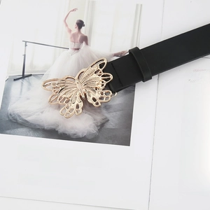 Detail shot of a black leather belt featuring a large polished gold butterfly buckle