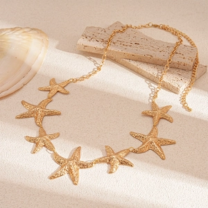 Macro shot of gold starfish waist chain texture on beige sandy stone background