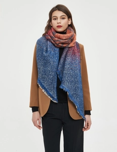 Detail of thick knit shawl scarf with blue to orange gradient and fringe edges