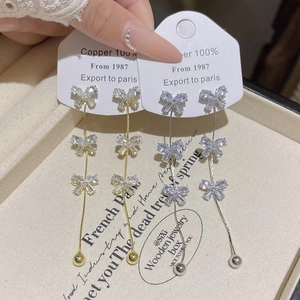 Macro shot of tiered bow tassel earrings in gold and silver finish with zircon stones