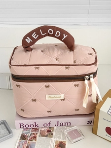 Close-up of pink quilted cosmetic bag with bow embroidery and Melody brand handle