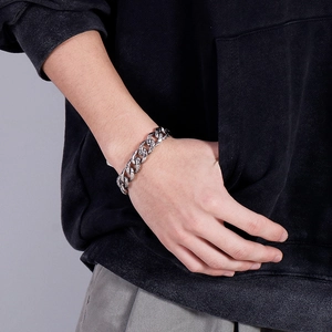 Men's stainless steel snake texture Cuban link bracelet worn on wrist over black hoodie