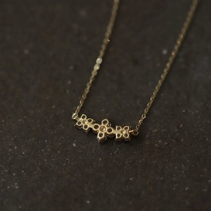 Macro shot of the polished gold-plated clover pendant back on dark textured stone