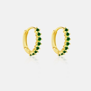 Close-up of gold huggie hoop earrings with six circular green emerald stones on reflective base