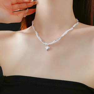 Close-up of a heart pendant pearl necklace worn by a model for elegant neck decoration