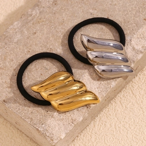 Macro view of wing-shaped 18K gold and silver plated metal charms on elastic hair ties