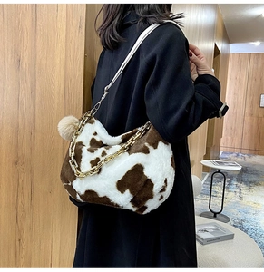 Detail of cow print plush tote with gold chain and white leather strap on model