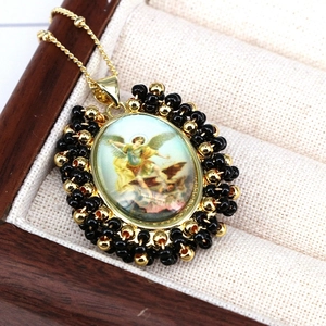 Macro shot of vintage oval religious pendant with black beads and gold wire wrapping