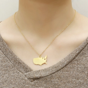 Close-up of a gold-plated USA map outline pendant necklace worn by a model in warm tones